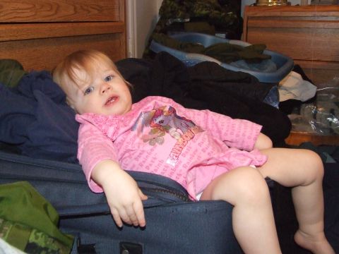 1990 Ford Bronco - A young child rests among laundry and luggage in a cluttered room.