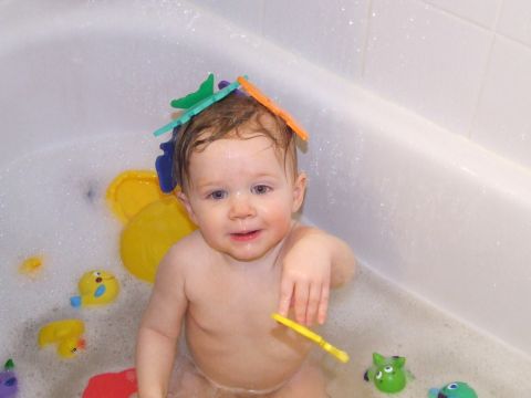 1990 Ford Bronco - A baby enjoys bath time with colorful toys floating in the water.