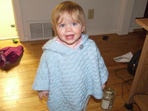 1990 Ford Bronco - A young child stands in a room wearing a blue knitted poncho.