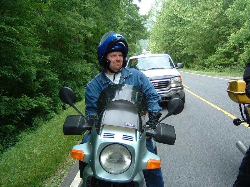 Man on motorcycle with white truck behind on a road