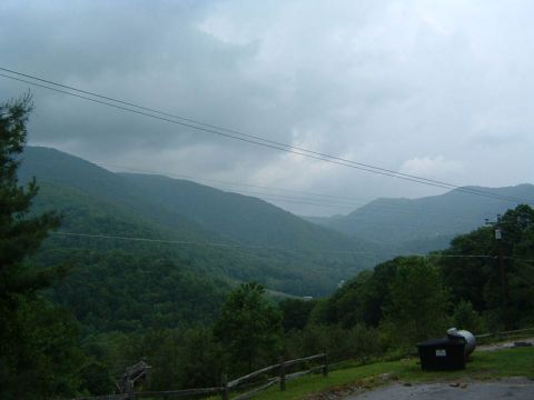 1985 Ford LTD Crown Victoria - A cloudy day over a lush, green mountain range.