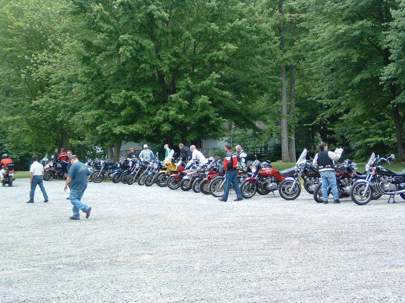 Group of people standing around a large parking lot filled with motorcycles