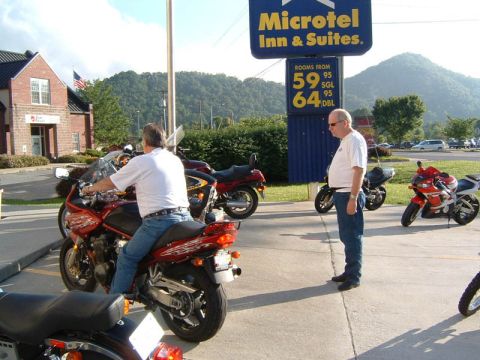 1985 Ford LTD Crown Victoria - Motorcycles are parked in front of a Microtel Inn & Suites, with two men visible.