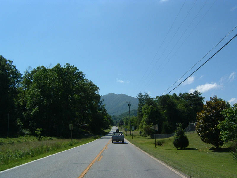 Driving down a two-lane road towards mountains, a truck is ahead