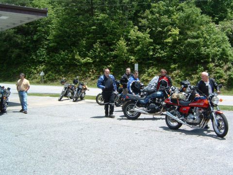 1985 Ford LTD Crown Victoria - A group of motorcyclists gather near their bikes at a roadside stop.