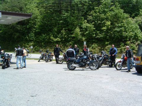 1985 Ford LTD Crown Victoria - Motorcyclists gather at a gas station, with several bikes parked and people socializing.