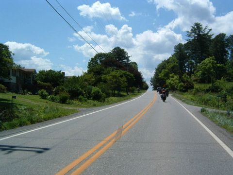 1985 Ford LTD Crown Victoria - Motorcycles travel down a rural highway on a sunny day.