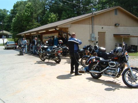 1985 Ford LTD Crown Victoria - A group of people and motorcycles are gathered outside a building.
