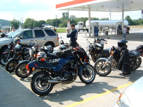 1985 Ford LTD Crown Victoria - A group of motorcycles are gathered at a gas station on a sunny day.
