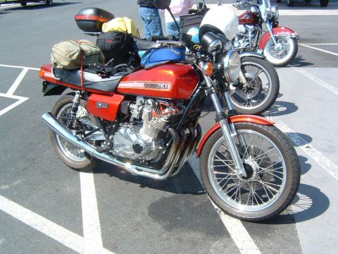 1985 Ford LTD Crown Victoria - A red Suzuki motorcycle is parked next to other motorcycles in a parking lot.
