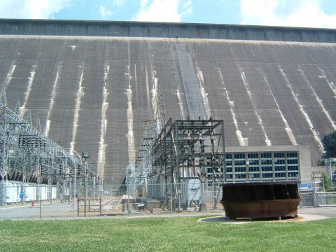1985 Ford LTD Crown Victoria - A large concrete dam with electrical infrastructure in front of it under a blue sky.