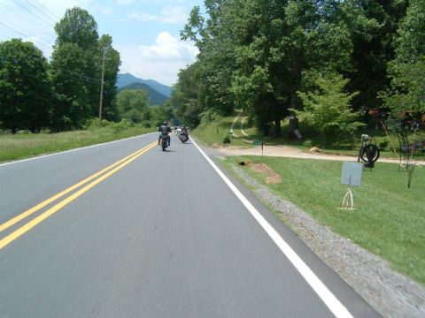 1985 Ford LTD Crown Victoria - A group of motorcycles travels down a rural highway on a sunny day.