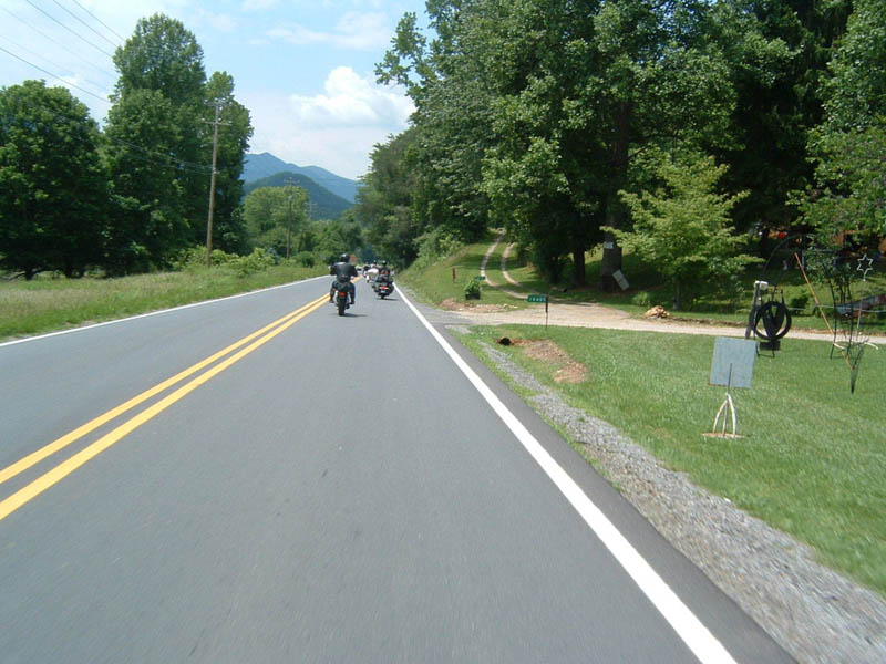 Several motorcycles riding down a two-lane road with mountains in the background