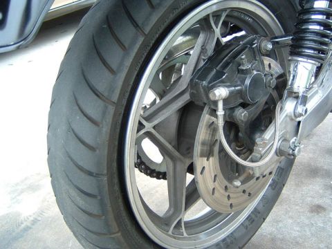 1985 Ford LTD Crown Victoria - The rear wheel assembly of a motorcycle, a disc brake and suspension components.