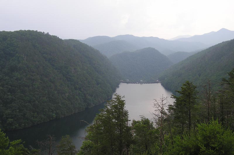 Mountainous terrain with a wide lake leading to a dam in the distance