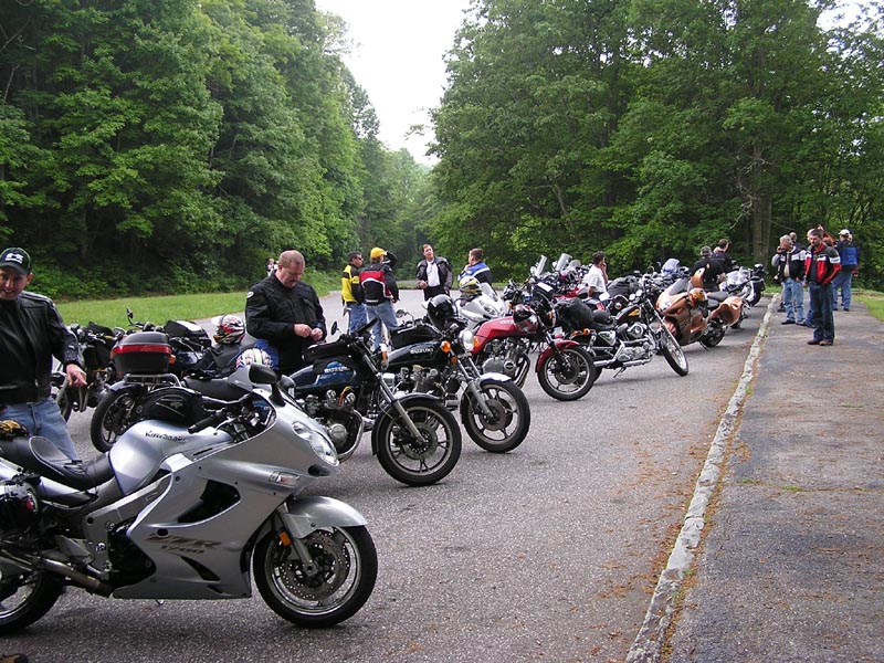 Silver sport motorcycle parked in a line with other motorcycles and riders