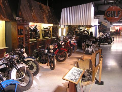 1985 Ford LTD Crown Victoria - A collection of antique motorcycles is displayed in a museum setting with various exhibits and signage.