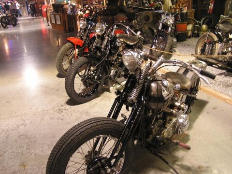 1985 Ford LTD Crown Victoria - Several custom motorcycles are lined up in a showroom, with the closest one in sharp focus.