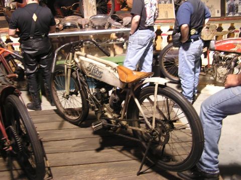 1985 Ford LTD Crown Victoria - A vintage Thor motorcycle is displayed indoors with several people observing it.