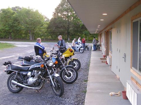 1985 Ford LTD Crown Victoria - Motorcyclists gather outside a motel, with several bikes parked in the lot.