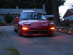 1997 Ford Probe - A red 1997 Ford Probe is parked in a driveway, its headlights illuminated.