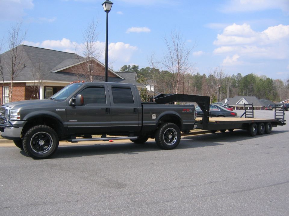 Dark gray 2005 Ford F-250 Super Duty truck with a gooseneck hitch, towing a triple-axle flatbed trailer