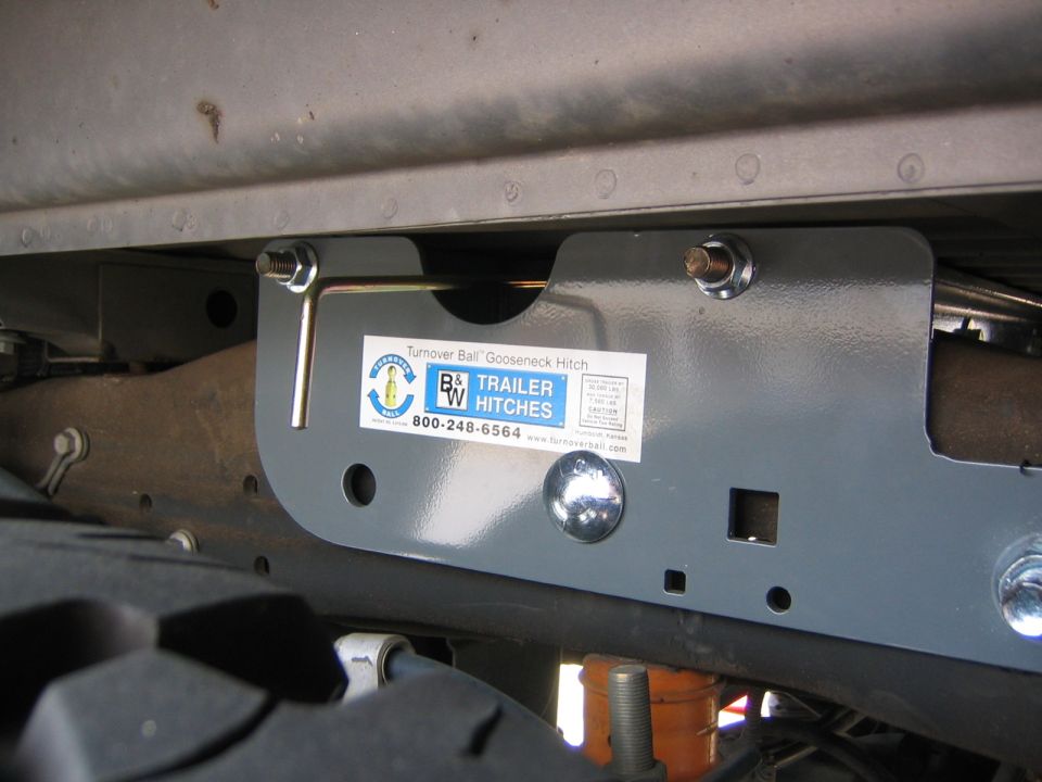 Trailer hitch assembly with B&W Trailer Hitches label, mounted to vehicle frame near tire