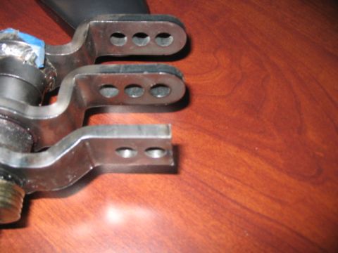 1991 Ford Bronco - Close-up view of metal linkage components, possibly from a vehicle's suspension or steering system, resting on a wood-grain surface.