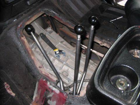 1991 Ford Bronco - A wrench rests on the transmission housing near the manual gear shift levers inside a vehicle.