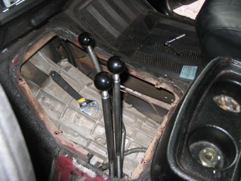 1991 Ford Bronco - The interior of a vehicle shows a transmission tunnel with three shifters and tools, suggesting maintenance or modification.