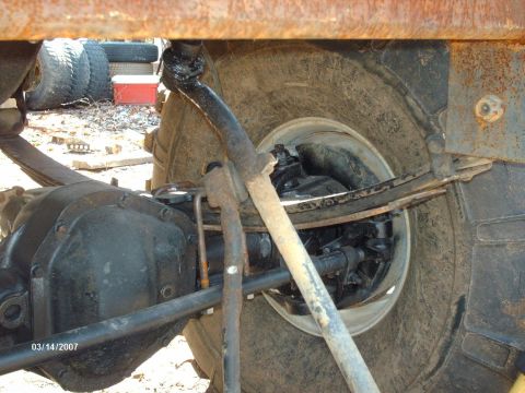 1990 Ford F-150 - Close-up view of a truck's rear axle and suspension components, with tires stacked in the background.