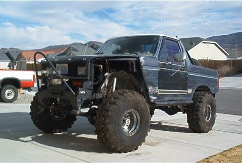 1986 Ford Bronco - Modified 1986 Ford Bronco with large off-road tires and a custom front end is parked outside.