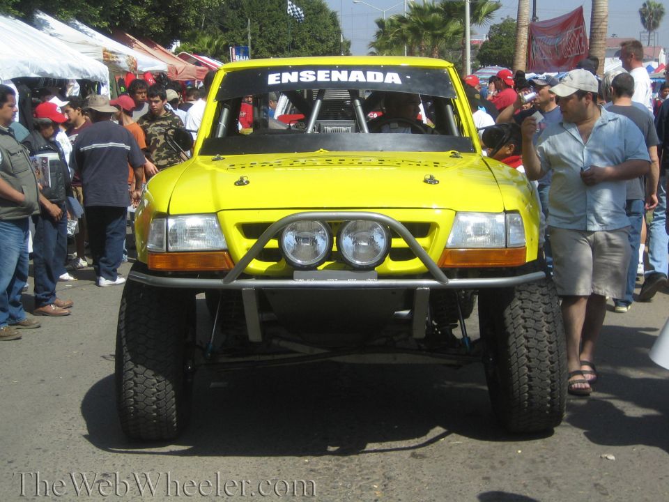 Front of yellow off-road race truck marked ENSENADA in a crowd