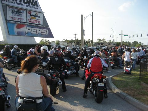 1986 Ford Bronco - A large group of motorcyclists are gathered near the Daytona International Speedway, with a Pepsi advertisement visible on the sign.