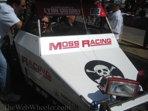 1990 Ford Bronco - Detail of a white race buggy showing red 'Moss Racing' lettering, a skull-and-crossbones decal, and number 1604 above the seats.