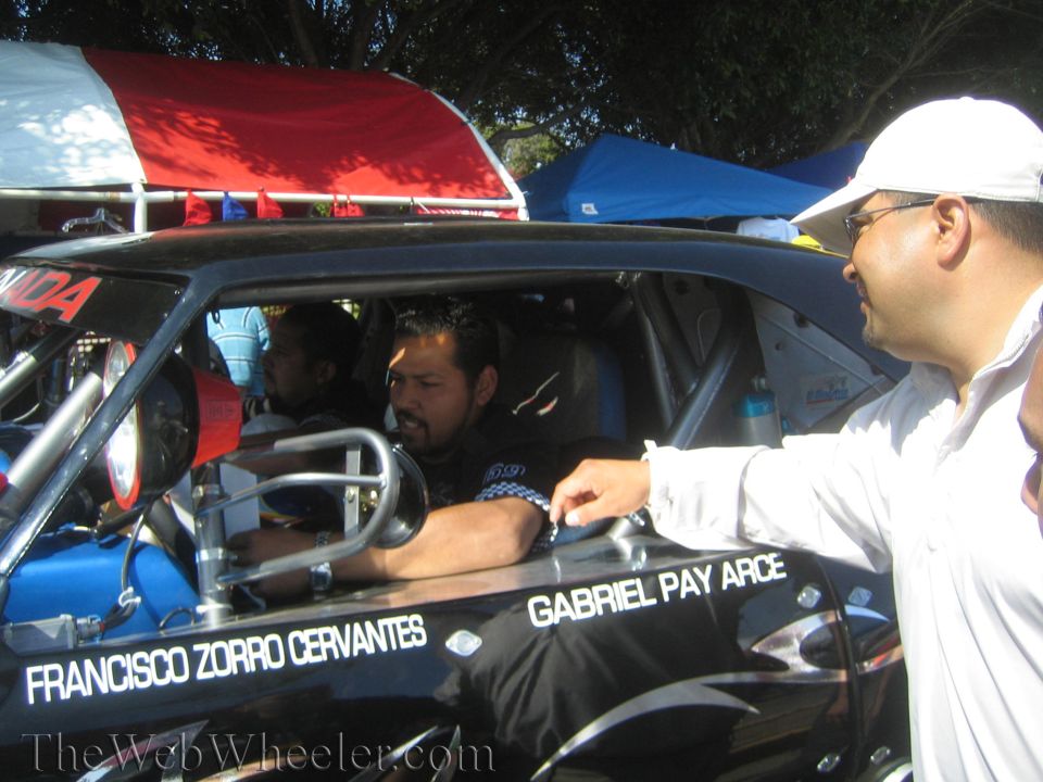 Men beside black race truck cockpit lettered Francisco Zorro Cervantes