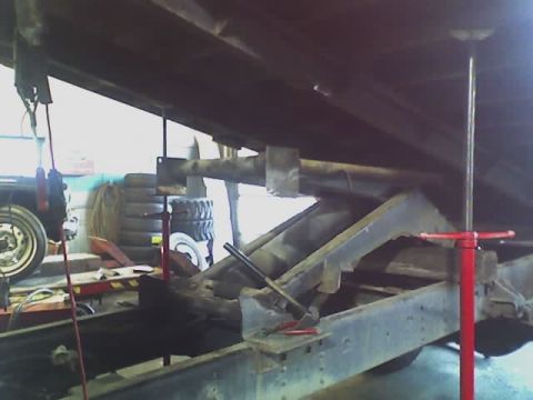 1992 Ford Bronco - The underside of a vehicle is visible, supported by a hydraulic lift system in a workshop.