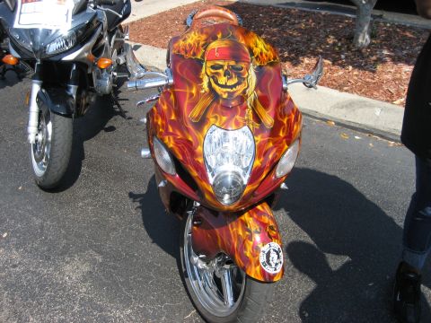 1986 Ford Bronco - A custom motorcycle with a pirate skull and flames paint scheme is parked on asphalt.