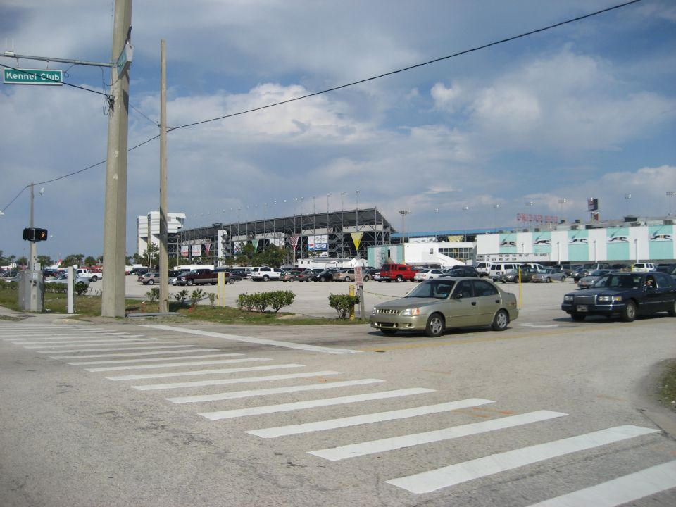 Parking lot with cars and stadium in background. Kennel Club sign visible