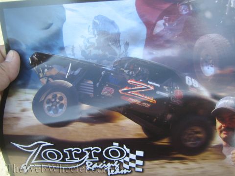 1990 Ford Bronco - hand holds a glossy 'Zorro Racing Team' poster showing a black number 69 trophy truck airborne over desert terrain.