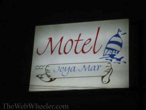 1990 Ford Bronco - illuminated white motel sign reads Motel Joya Mar in red and blue script with a sailboat graphic, glowing against the night.