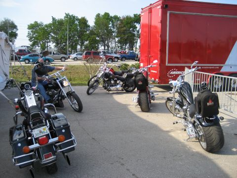 1986 Ford Bronco - Motorcycles gathered outdoors near a large red trailer, with cars in the background.