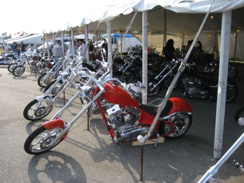 1986 Ford Bronco - Multiple custom choppers are lined up under a white tent at an outdoor event.