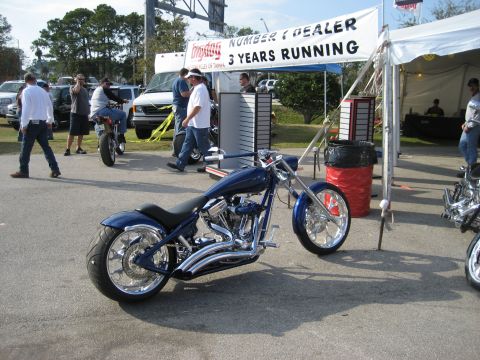 1986 Ford Bronco - A custom blue motorcycle with chrome details is displayed at an outdoor event, with a banner in the background.