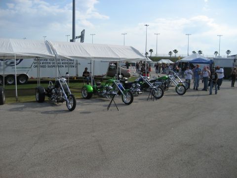 1986 Ford Bronco - A collection of custom motorcycles and a trike are displayed outdoors under tents, with a trailer in the background.