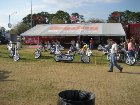1986 Ford Bronco - A variety of custom motorcycles are displayed outdoors under a large tent with a prominent logo.