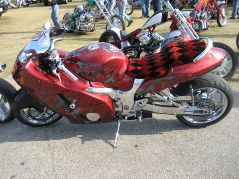 1986 Ford Bronco - A custom red motorcycle with flame graphics and a checkered seat is parked outdoors among other vehicles.
