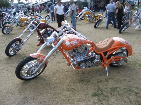 1986 Ford Bronco - A collection of custom choppers are displayed outdoors, with people milling around in the background.