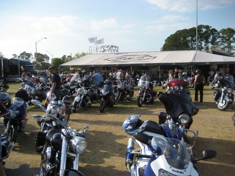 1986 Ford Bronco - A large gathering of motorcycles parked outdoors under a tented structure with attendees milling about.