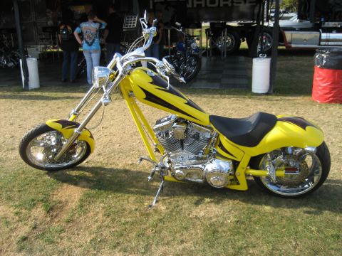 1986 Ford Bronco - A yellow custom chopper motorcycle is displayed outdoors with chrome accents and flame graphics.